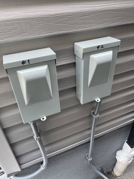 Two labeled electrical disconnect boxes mounted on exterior wall