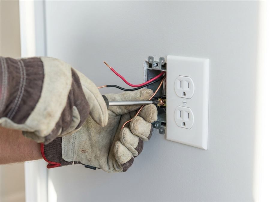 Electrician rewiring a wall outlet